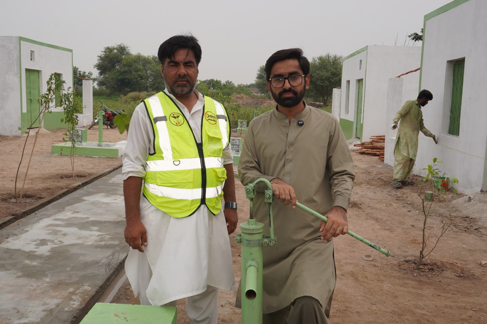 Foundation field team beside a community hand pump